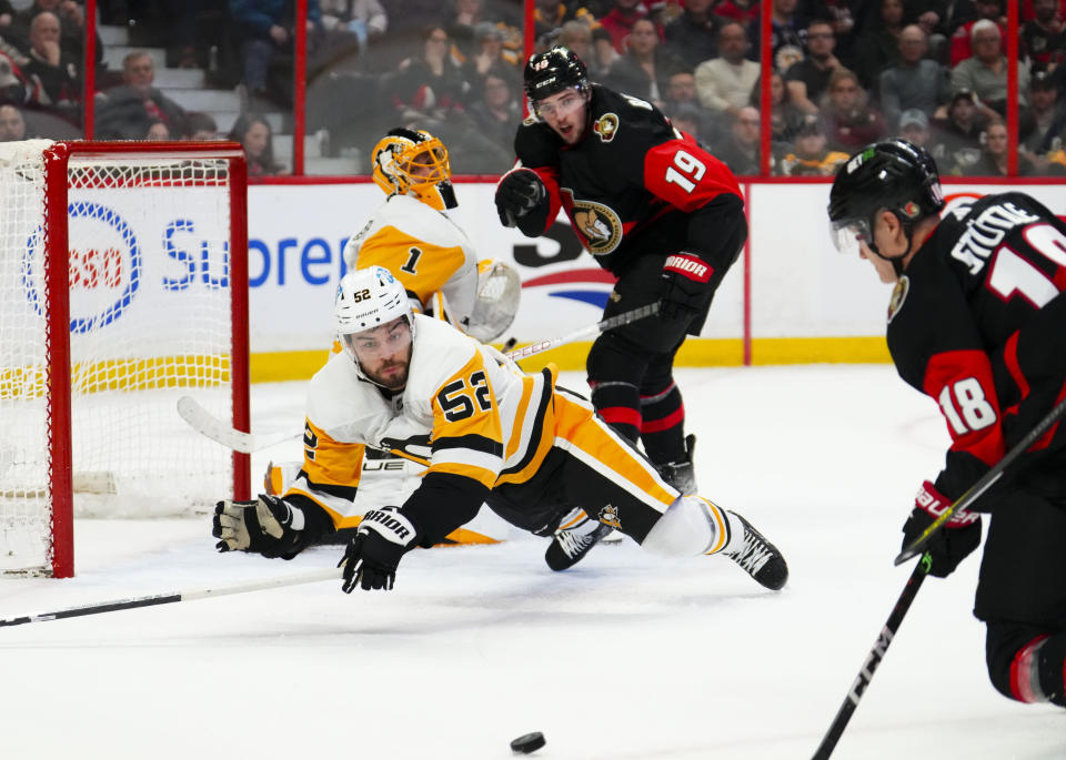 Pittsburgh Penguins defenseman Mark Friedman (52) dives in front of the net as Ottawa Senators left wing Tim Stützle (18) attempts a shot during the second period of an NHL hockey game Wednesday, Jan. 18, 2023, in Ottawa, Ontario. (Sean Kilpatrick/The Canadian Press via AP)