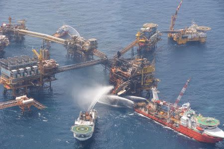 Boats spray water to extinguish a fire on the Abkatun Permanente oil processing platform in Campeche in this April 2, 2015 handout photo by Pemex. REUTERS/Pemex/Handout via Reuters