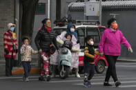 Residents, some wearing masks, cross a road in Beijing, China, Wednesday, Oct. 20, 2021. China's capital Beijing has begun offering booster shots against COVID-19, four months before the city and surrounding regions are to host the Winter Olympics. (AP Photo/Ng Han Guan)