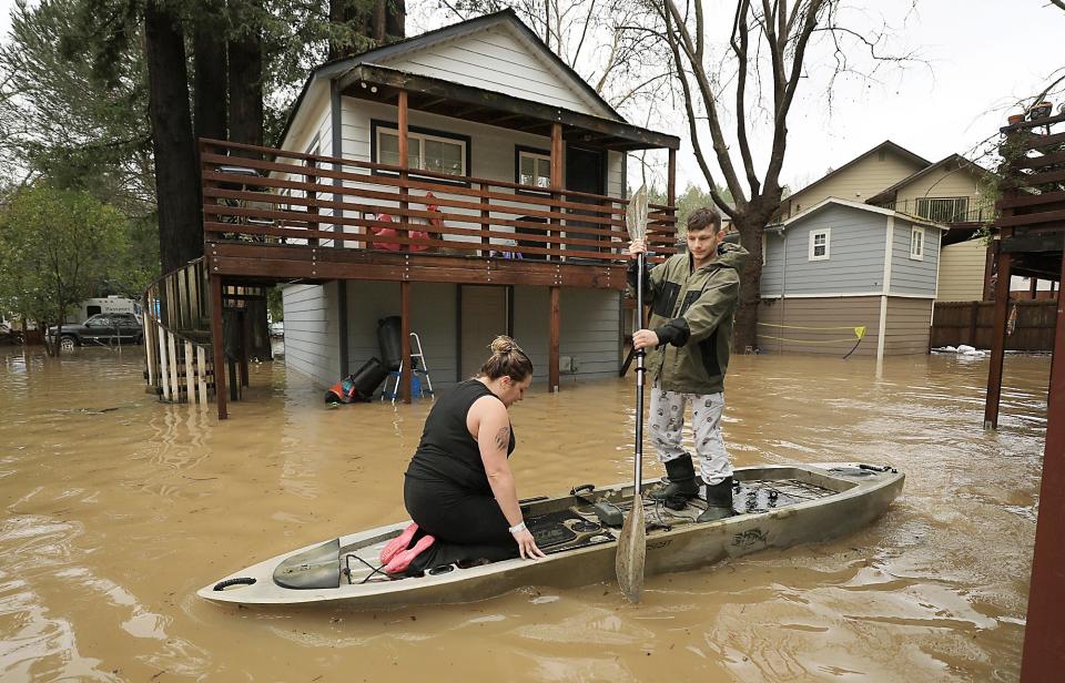 Residents of Sycamore Court flooded by Armstrong Creek, who declined to give their names, paddle out of high water from their apartment in Guerneville (AP)