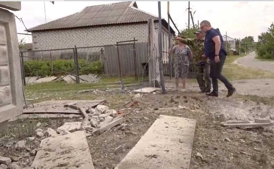 This image taken from a video shows people indicating a damaged building in the Belgorod region, Russia, Monday, May 22, 2023. Russian troops and security forces fought for a second day Tuesday against an alleged cross-border raid that Moscow blamed on Ukrainian military saboteurs but which Kyiv portrayed as an uprising against the Kremlin by Russian partisans. Vyacheslav Gladkov, governor of the Belgorod region on the Ukraine border, said forces continued to sweep the rural area around the town of Graivoron, where the alleged attack on Monday took place. (AP Photo)