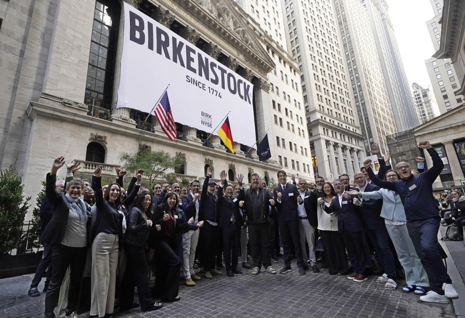 Birkenstock CEO Oliver Reichert, center, and company employees pose for photos outside the New York Stock Exchange, prior to his company's IPO, Wednesday, Oct. 11, 2023. (AP Photo/Richard Drew)