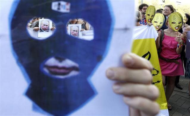 Activists wear masks in support of members of the female punk band Pussy Riot and hold banners depicting Russian President Vladimir Putin during a protest in front of the Russian delegation to the European Union in Brussels August 17, 2012.