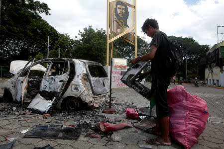 A man stands next to a burned car after a protest against Nicaraguan President Daniel Ortega's government in Managua, Nicaragua May 31, 2018.REUTERS/Oswaldo Rivas