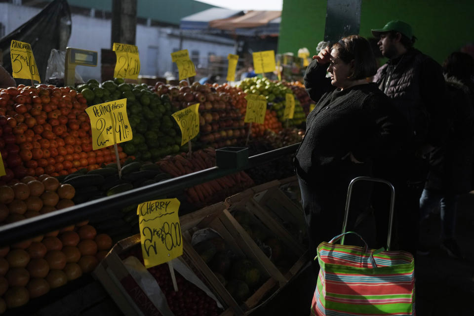 FILE - A shopper uses her hand to shade herself from the sun as she reviews the prices at a produce stand, in Buenos Aires, Argentina, Sept. 1, 2023. Argentines are faced with one of the highest inflation rates in the world. (AP Photo/Natacha Pisarenko, File)