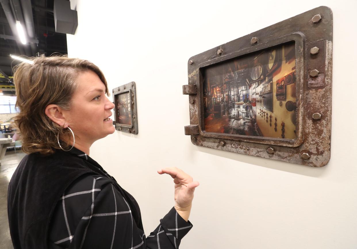 Karen Starr of Hazel Tree Design Studio talks at Bounce Innovation Hub in Akron about a coal hatch flange that was repurposed as a picture frame with a photo printed on metal capturing the interior of the old B.F. Goodrich power plant.