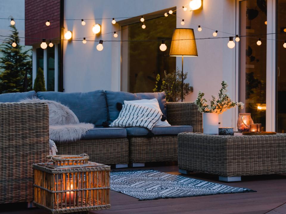 string lights hanging in outdoor seating area and a wicker furniture set with blue cushions