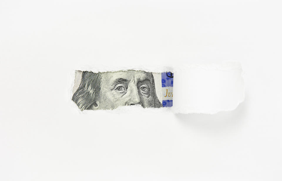 Benjamin Franklin portrait on one hundred dollar bill in torn paper hole, close-up