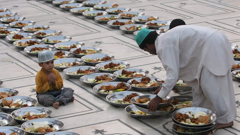 A Pakistani Muslim arranges food stuff for 'Iftar', a time to break the fast, on the first day of holy fasting month of Ramadan  as a child looks on at a mosque in Karachi, Pakistan, Sunday, Aug. 23, 2009.