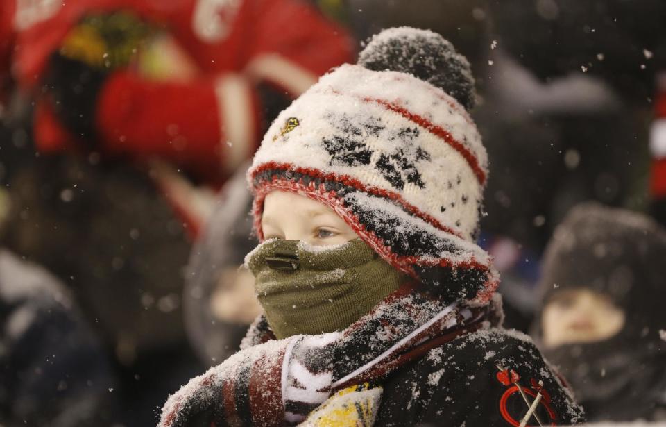 A young hockey fan watches the Chicago Blackhawks face the Pittsburgh Penguins as snow falls during the first period of an NHL Stadium Series hockey game at Soldier Field on Saturday, March 1, 2014, in Chicago. (AP Photo/Charles Rex Arbogast)