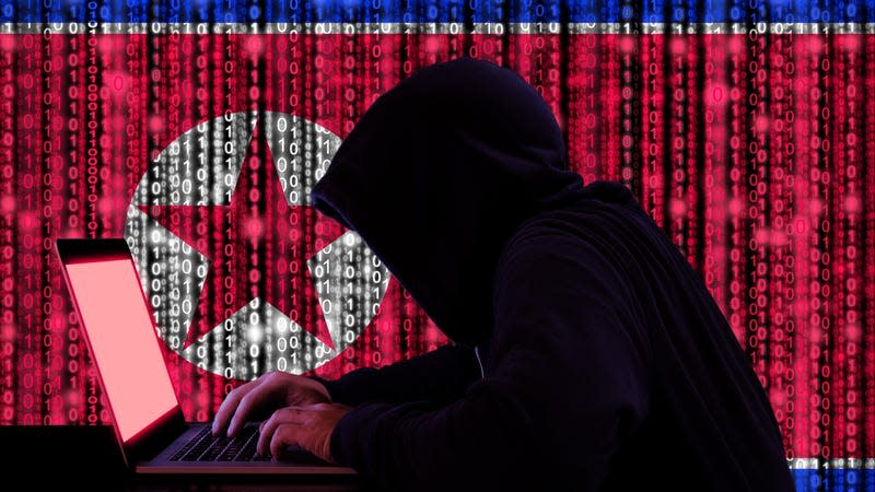 The black silhouette of a hacker on a computer is shown against a North Korean flag.