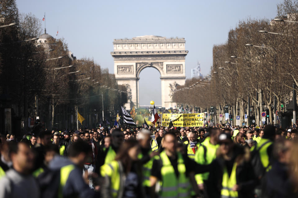 Yellow vest protesters walk down the famed Champs Elysees avenue, in Paris, France, Saturday, Feb. 23, 2019. French yellow vest protest organizers are trying to tamp down violence and anti-Semitism in the movement's ranks as they launch a 15th straight weekend of demonstrations. (AP Photo/Kamil Zihnioglu)