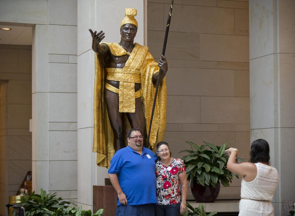 Gary Phillips Jr., and his mother, Carol Phillips, visiting the U.S. Capitol from Kailua, Hawaii, pose for a souvenir photo beneath the towering bronze statue of King Kamehameha, the 18th century Hawaiian warrior-monarch, at the Capitol Visitors Center in Washington, Tuesday, July 2, 2013. Phillips claims a tenth generation relation to Kamehameha on the side of the ruler's wife, Kanekapolei. American sculptor Thomas R. Gould depicted Kamehameha in his gilded robe and loincloth. It is the heaviest statue in the National Statuary Hall Collection. (AP Photo/J. Scott Applewhite)