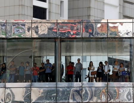 People watch a protest rally go by from a bridge, in Hong Kong