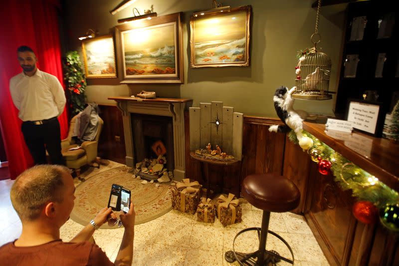 Man takes pictures of an artwork dubbed "scar of Bethlehem" by street artist Banksy in the Walled Off hotel, in Bethlehem in the Israeli-occupied West Bank