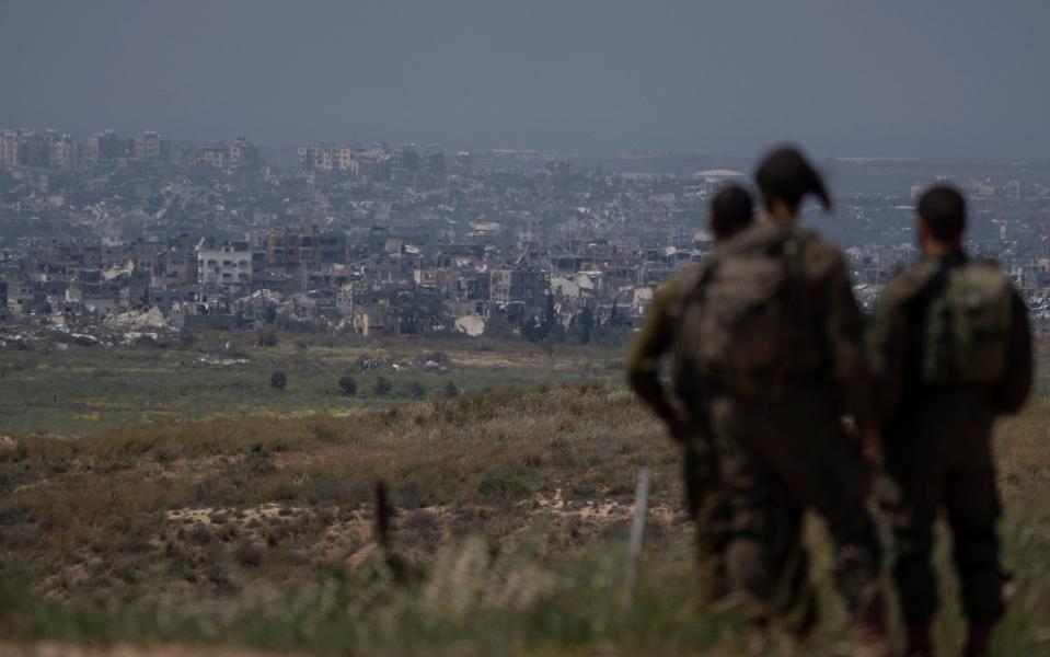 Israeli soldiers look at destroyed buildings in the Gaza Strip