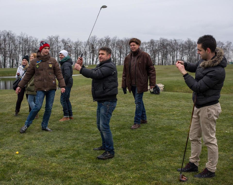 Protesters try to play on a golf course at the Ukrainian President Yanukovych's countryside residence in Mezhyhirya, Kiev's region, Ukraine, Saturday, Feb, 22, 2014. Viktor Yanukovych is not in his official residence of Mezhyhirya, which is about 20 kilometres north of the capital. Ukrainian security and volunteers from among Independence Square protesters have joined forces to protect the presidential countryside retreat from vandalism and looting.(AP Photo/Andrew Lubimov)