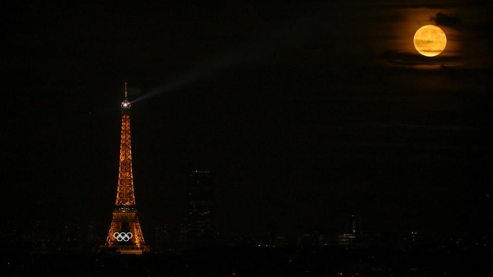     This photo shows the Olympic Rings on the Eiffel Tower, at night, with a full moon shining, in preparation for the Paris 2024 Olympic and Paralympic Games, which will take place in Paris on July 21, 2024. 