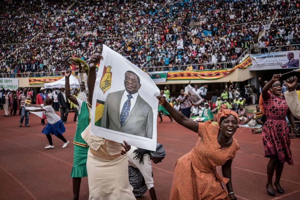 <p>TOPSHOT – Supporters hold poster of the newly sworn-in President Emmerson Mnangagwa during the Inauguration ceremony at the National Sport Stadium in Harare, on November 24, 2017.<br> Zimbabwe’s newly sworn-in President Emmerson Mnangagwa vowed during his inauguration speech on November 24 to protect foreign investments in the country as he sought to lay out his economic credentials. “In this global world no nation is, can, or need be an island. All foreign investments will be safe in Zimbabwe,” he told a crowd of tens of thousands at his inauguration ceremony. (Photo: Marco Longari/AFP/Getty Images) </p>