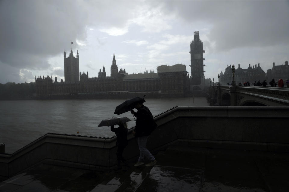 People are silhouetted with umbrellas in the rain backdropped by the Houses of Parliament in London, Tuesday, Sept. 24, 2019. In a major blow to Prime Minister Boris Johnson, Britain's highest court ruled Tuesday that his decision to suspend Parliament for five weeks in the crucial countdown to the country's Brexit deadline was illegal. (AP Photo/Matt Dunham)