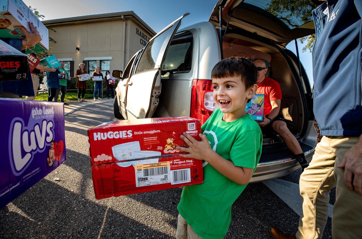 T.J. Moreno, a 5-year-old Lakeland boy, helps unload a van full of diapers Thursday afternoon at One More Child as staff and volunteers relay them toward a pile in front of the Harold Clark Simmons Compassion Center in Lakeland. T.J. and his parents donated 162 boxes of diapers in the second year the boy has led a collection campaign.