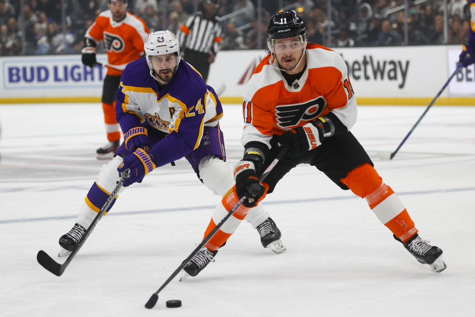 Philadelphia Flyers forward Travis Konecny, right, prepares to shoot next to Los Angeles Kings forward Phillip Danault (24) during the first period of an NHL hockey game Saturday, Dec. 31, 2022, in Los Angeles. (AP Photo/Ringo H.W. Chiu)