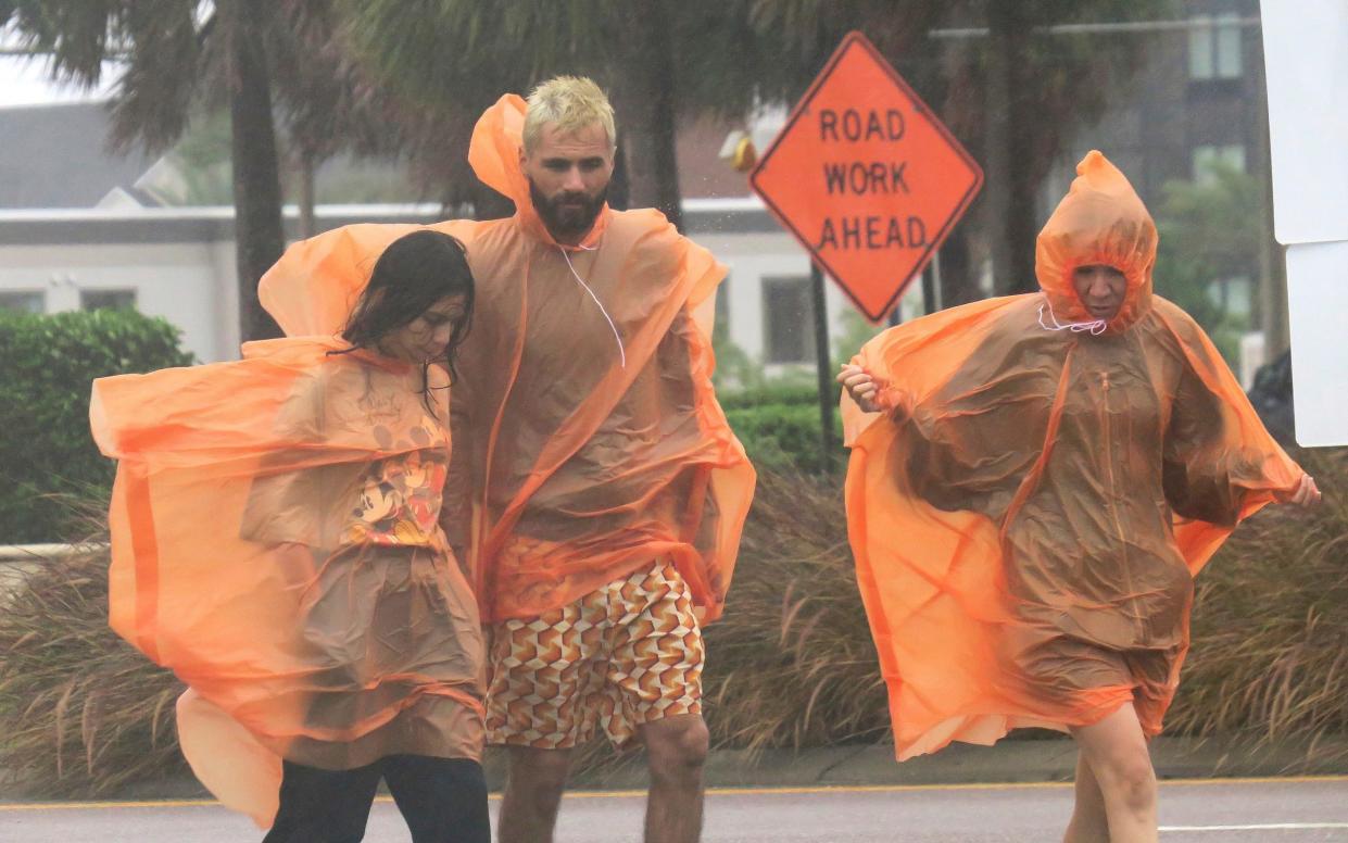 People in raincoats walk along International Drive in Orlando - Joe Burbank /Orlando Sentinel 