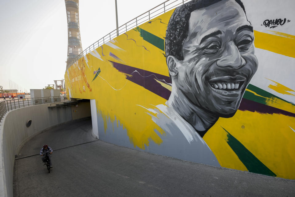 A man rides past a mural of Brazilian soccer star Pele outside the Khalifa International Stadium in Doha, Qatar, Saturday, Dec. 3, 2022. (AP Photo/Ricardo Mazalan)