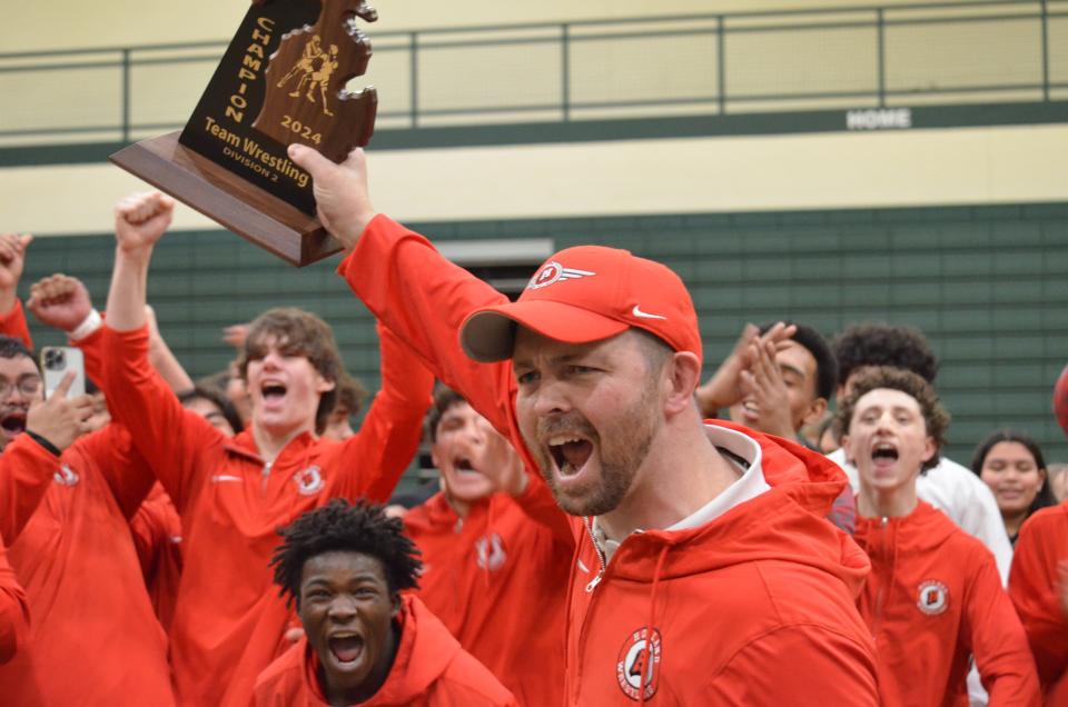 Holland wrestling coach Nick Lewin celebrates with his team after clinching the Division 2 district championship on Thursday, Feb. 8, 2024, at Zeeland West.