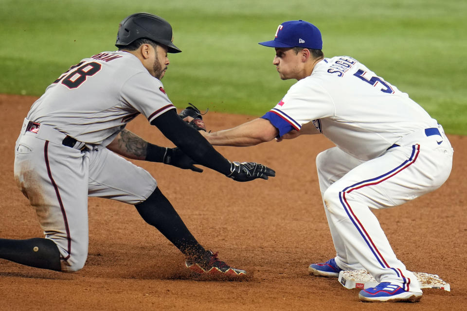 Arizona Diamondbacks' Tommy Pham (28) is tagged out by Texas Rangers shortstop Corey Seager (5) while trying to get back to second base during the sixth inning in Game 2 of the baseball World Series Saturday, Oct. 28, 2023, in Arlington, Texas. (AP Photo/Julio Cortez)