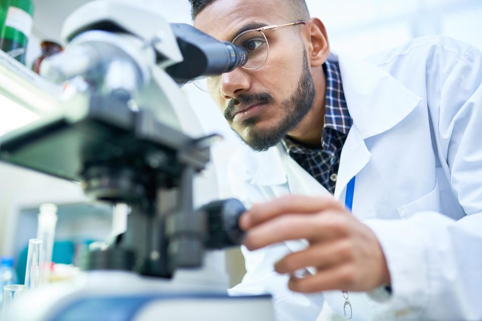 Guy in a lab coat using a microscope.