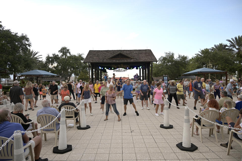 FILE - People dance in the Lake Sumter Landing Market Square, Thursday, Aug. 12, 2021, in The Villages, Fla. A wave of retirements, a drop in legal immigration, and hundreds of thousands of COVID-19 deaths have left the U.S. with a smaller workforce than when the pandemic began two and half years ago, a change that could bolster wage growth and inflation and force the Federal Reserve to keep interest rates higher for longer. (AP Photo/Phelan M. Ebenhack, File)