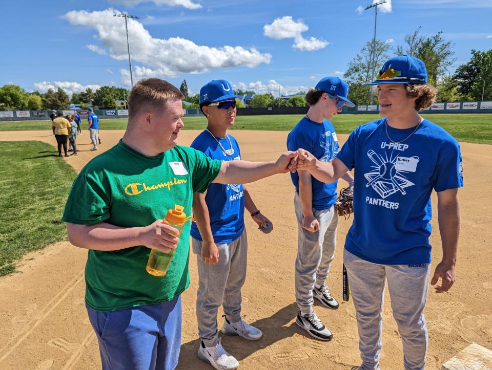 Enterprise student Garrett Fitzgerald (center) fist bumps U-Prep senior outfielder Bailey Wurzer (right) and is joined by U-Prep senior second baseman Mason Miyamoto (back center) and catcher Mason Cassingham (back right) at the first Baseball 4 All at Tiger Field on Wednesday, May 3, 2023.