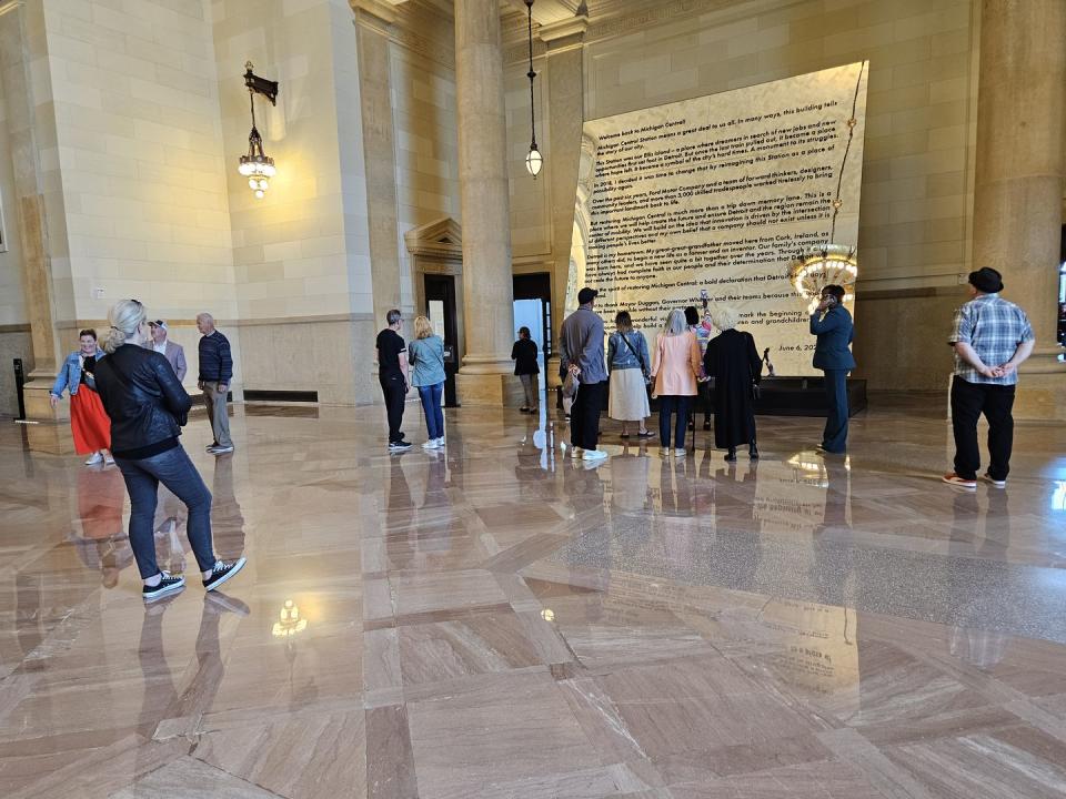 a group of people in a large room with columns and a large statue