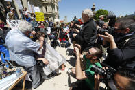 The media record barber Karl Manke, of Owosso, giving a free haircut to Parker Shonts on the steps of the State Capitol during a rally in Lansing, Mich., Wednesday, May 20, 2020. Barbers and hair stylists are protesting the state's stay-at-home orders, a defiant demonstration that reflects how salons have become a symbol for small businesses that are eager to reopen two months after the COVID-19 pandemic began. (AP Photo/Paul Sancya)