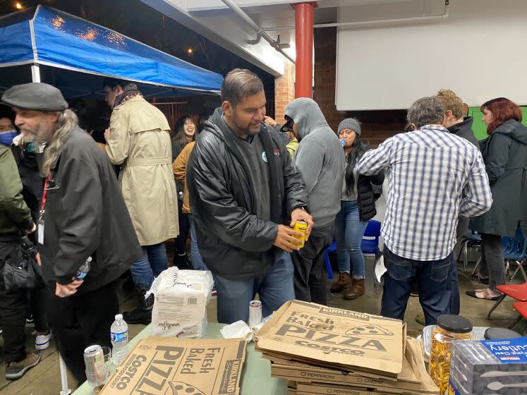 At a Democratic Socialist of America Los Angeles chapter election night party, Hugo Soto-Martinez prepares to snack on Costco pizza at an election night party in Los Angeles, on Tuesday, Nov. 8, 2022.