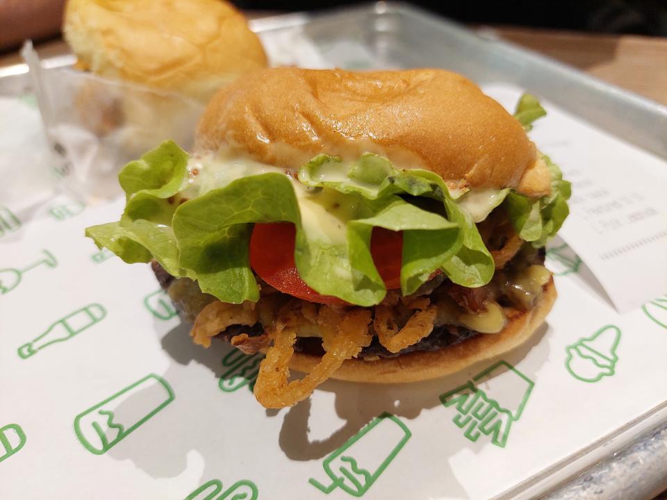 The crispy shallot vegan burger from Shake Shack, displayed on a tray