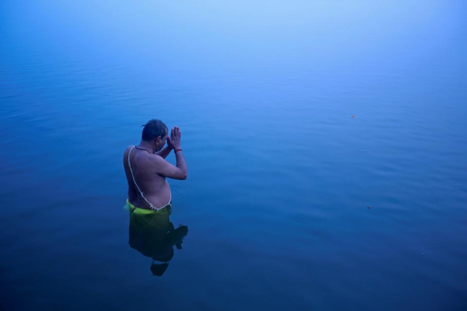 A Hindu devotee stands in the waters of river Ganges to offer prayers to Sun god at dawn in Varanasi, in the northern Indian state of Uttar Pradesh