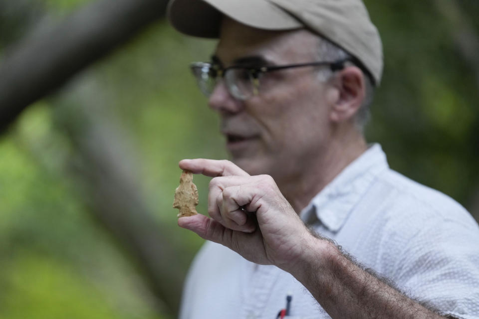 Professor Mark Rees, of the University of Louisiana at Lafayette, and director of the Louisiana Public Archeology Lab, holds a side notched, archaic projectile point at an archeological dig site in Kisatchie National Forest, La., Wednesday, June 7, 2023. This summer, archaeologists have been gingerly digging up the ground at the site in Vernon Parish to unearth and preserve the evidence of prehistoric occupation. The site was found by surveyors in 2003, according to the U.S. Forest Service. Hurricanes Laura and Delta uprooted trees and exposed some of the artifacts. Further damage has been done by looters making unauthorized digs. Forest officials say the site shows evidence of generations of people living in the area going back 12,000 years. (AP Photo/Gerald Herbert)