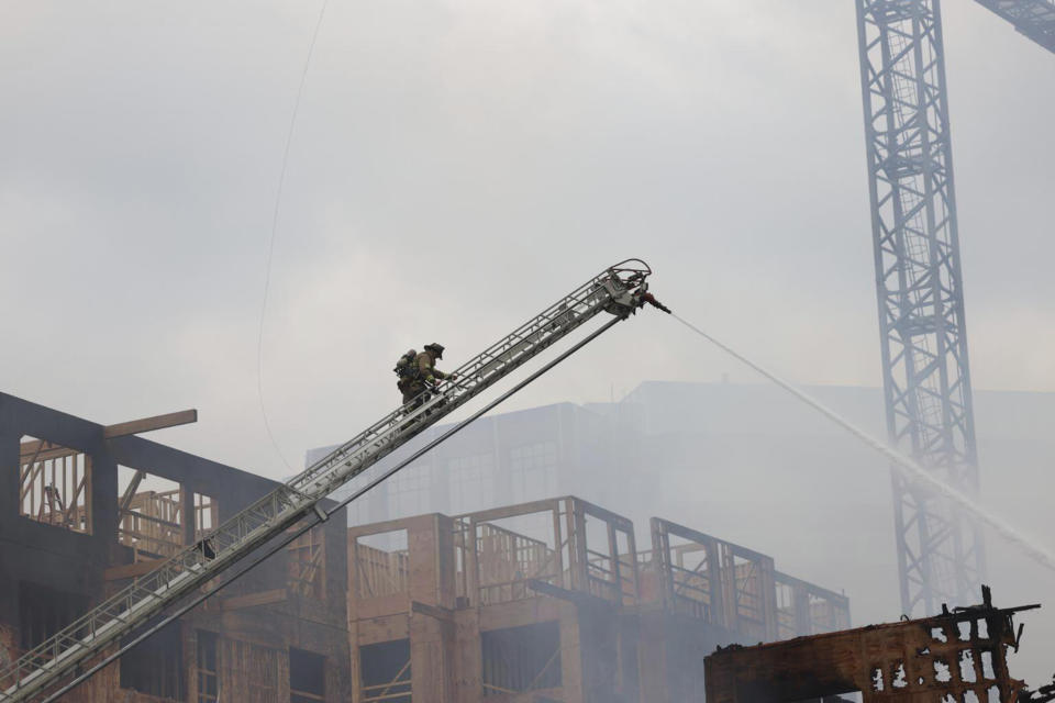 Firefighters work the scene of a massive fire spread across at least two structures and threatened others in Charlotte's South Park neighborhood, North Carolina, Thursday morning, May 18, 2023. (Khadejh Nikouyeh/The Charlotte Observer via AP)