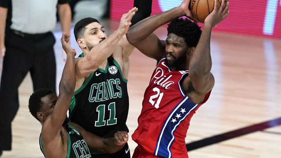 Joel Embiid is pictured trying to pass the ball against Boston's Enes Kanter and Kemba Walker.