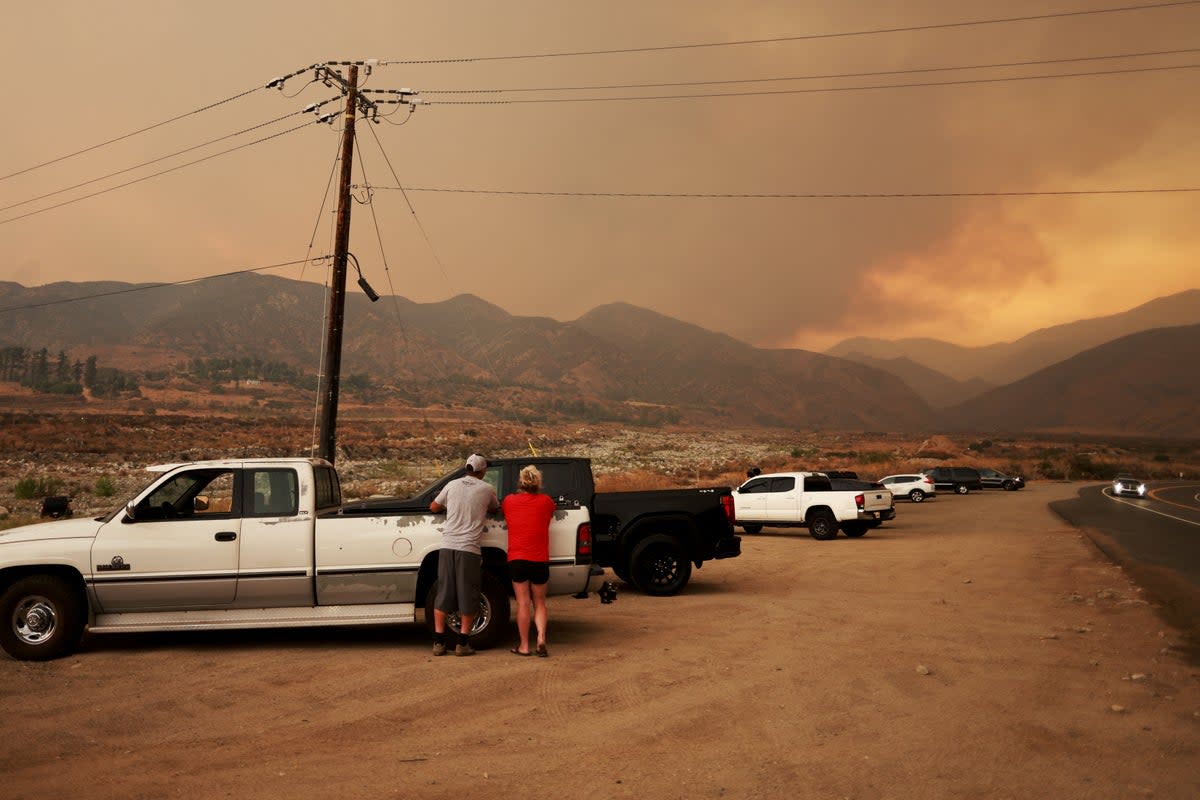 People watch the smoke column of the Line Fire as  it burns near Mentone, California, on Sunday. The fire is just 3 percent contained, but it continued to grow from Sunday to Monday, jumping past 21,000 acres. ((Photo by DAVID SWANSON/AFP via Getty Images))