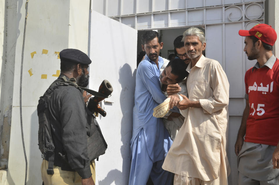 People comfort a relative of a police officer killed during a shootout at the Chinese Consulate in Karachi, Pakistan, Friday, Nov. 23, 2018. Armed separatists stormed the Chinese Consulate in Pakistan's southern port city of Karachi on Friday, triggering an intense hour-long shootout during which two police officers and all three assailants were killed, Pakistani officials said. (AP Photo/Shakil Adil)