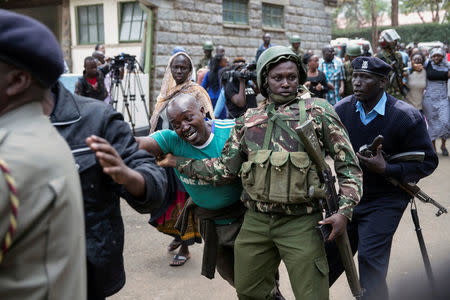 Kenyan police officers prevent a relative from entering the scene where seven Kenyan teenage schoolgirls died and 10 more were hospitalized after a fire engulfed their boarding school dormitory in Nairobi, Kenya September 2, 2017. REUTERS/Baz Ratner