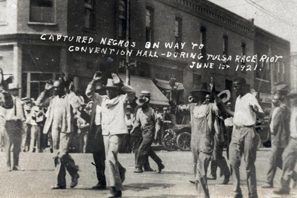 FILE - In this photo provided by the Department of Special Collections, McFarlin Library, The University of Tulsa, a group of Black men are marched past the corner of 2nd and Main Streets in Tulsa, Okla., under armed guard during the Tulsa Race Massacre on June 1, 1921. On May 31, 1921, carloads of Black residents, some of them armed, rushed to the sheriff's office downtown to confront whites who were gathering apparently to abduct and lynch a Black prisoner in the jail. Gunfire broke out, and over the next 24 hours, a white mob inflamed by rumors of a Black insurrection stormed the Greenwood district and burned it, destroying all 35 square blocks. Estimates of those killed ranged from 50 to 300. (Department of Special Collections, McFarlin Library, The University of Tulsa via AP, File)