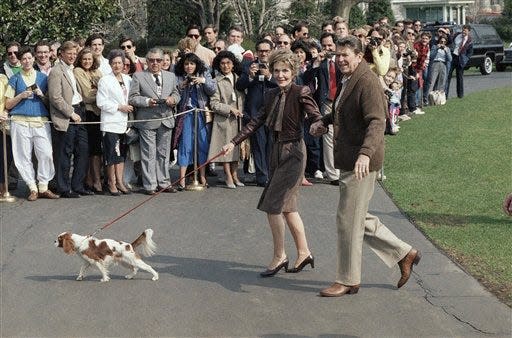 President Ronald Reagan, right, and First Lady Nancy Reagan, center, walk with their dog Rex on the South Lawn of the White House after they returned by helicopter from Camp David, Md. where the first family has spent the weekend, March 16, 1986, Washington, D.C. (AP Photo/Dennis Cook)