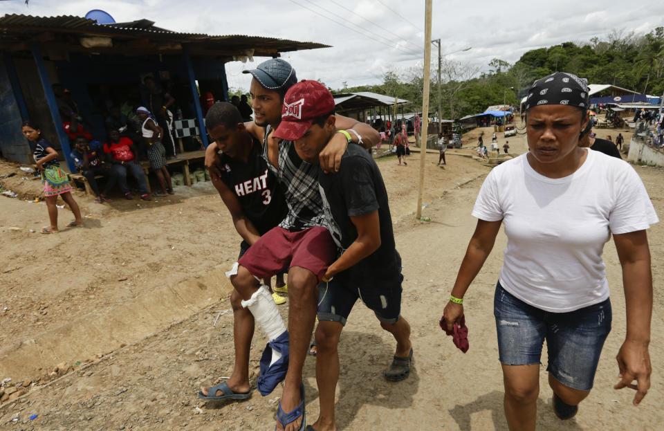 En esta imagen, tomada el 25 de mayo de 2019, el migrante cubano Alexis Bello Vargas es llevado por otros dos migrantes tras recibir un disparo en una pierna, en Peñitas, en la provincia de Darién, Panamá. Bello contó que su grupo se adentró en la selva, donde fueron interceptados por un grupo de ladrones armados, que abrieron fuego y se llevaron lo que les quedaba de sus pocas pertenencias, además de provocarle una herida en la pierna. (AP Foto/Arnulfo Franco)