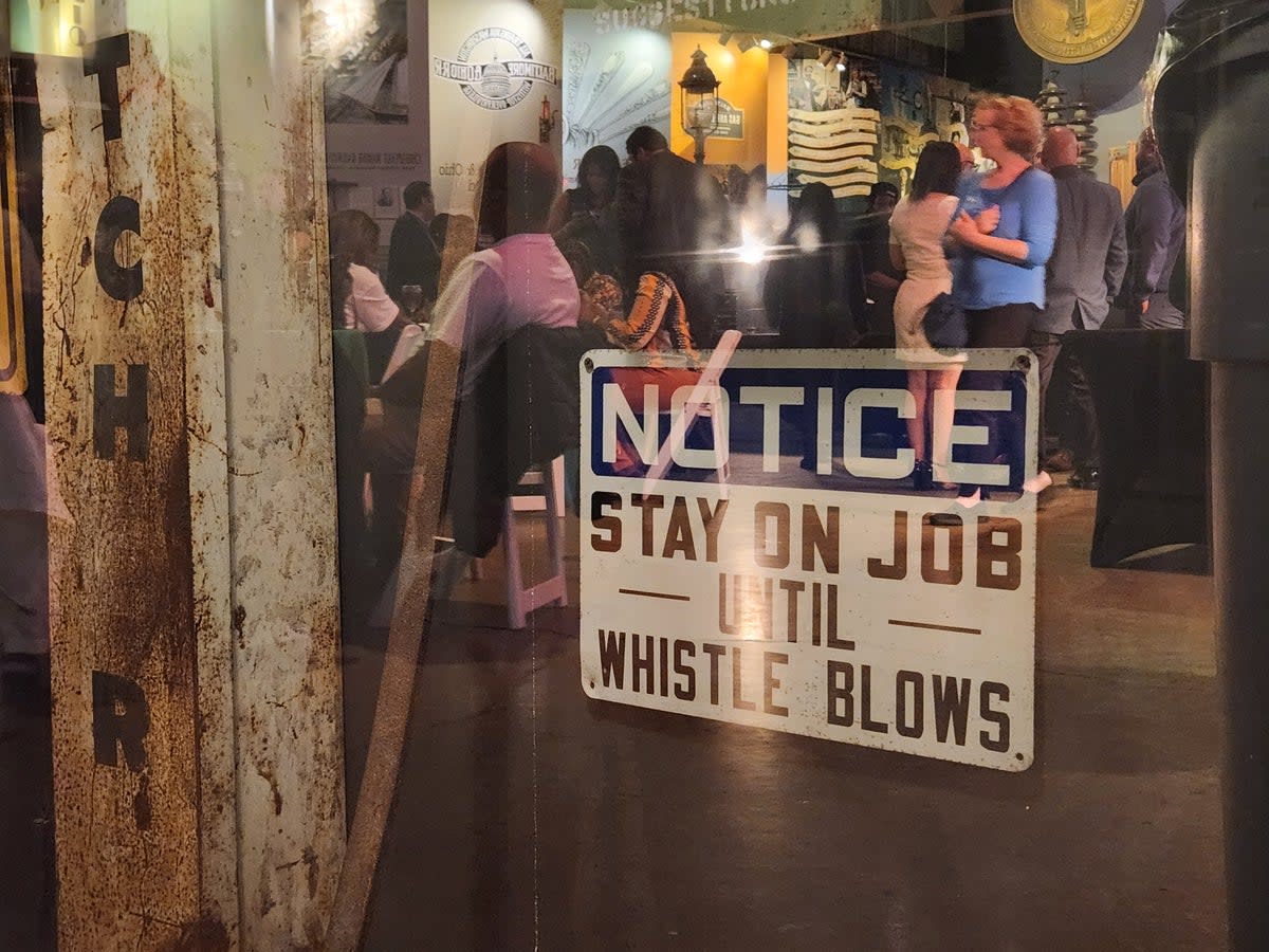 Attendees of David Trone’s election night watch event are reflected in the glass protecting an exhibit at the Baltimore Museum of Industry (John Bowden)