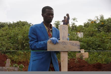 A Congolese man holds a cross during the burial service of Congolese woman Kahambu Tulirwaho who died of Ebola, at a cemetery in Butembo