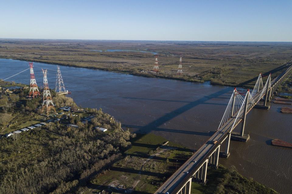 Technicians work to dismantle Tower 412, the tower on the water, third from left, and replace it with a new one, at far left, in the Litoral corredor near the town of Zarate, on the border of Buenos Aires and Entre Rios provinces, Argentina, Wednesday, June 19, 2019. Located in the Parana River, Tower 412 hasn't been operational since April so that workers could build the new tower to replace it and a bypass system had been set up to handle the current. Argentina's government suggested the origin of Sunday's blackout may stem from this corredor, and hopes to give a detailed explanation of events in twelve days time once all the technical elements have been analyzed. (AP Photo/Tomas F. Cuesta)